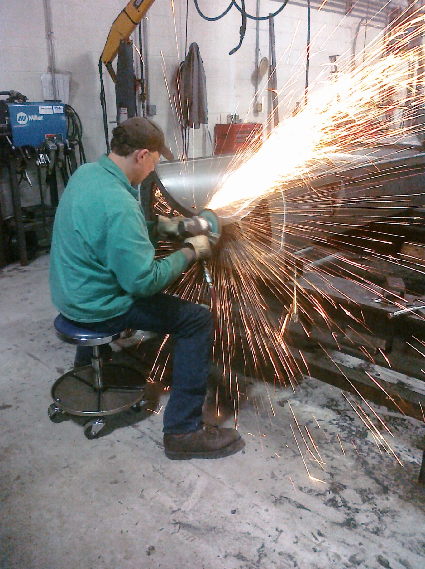 Fabricator grinding metal with sparks