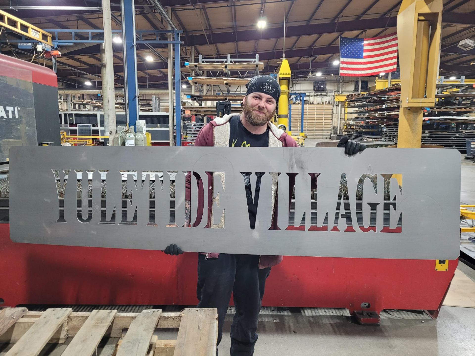 Laser cut Yuletide Village metal sign held by fabricator